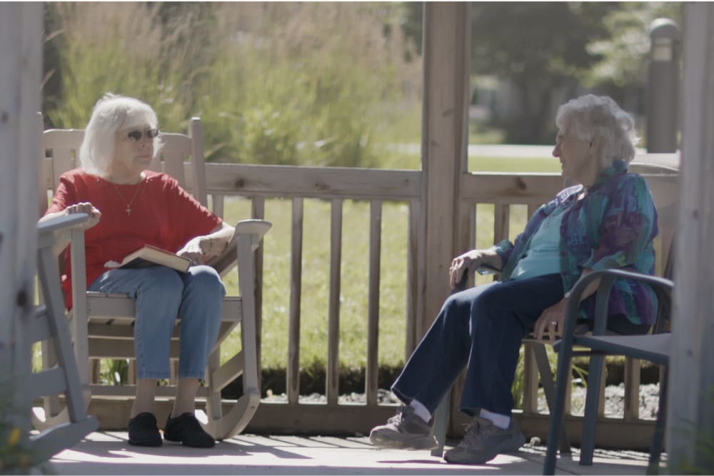 Two residents sitting outside on a sunny day at a Anthology Senior Living community